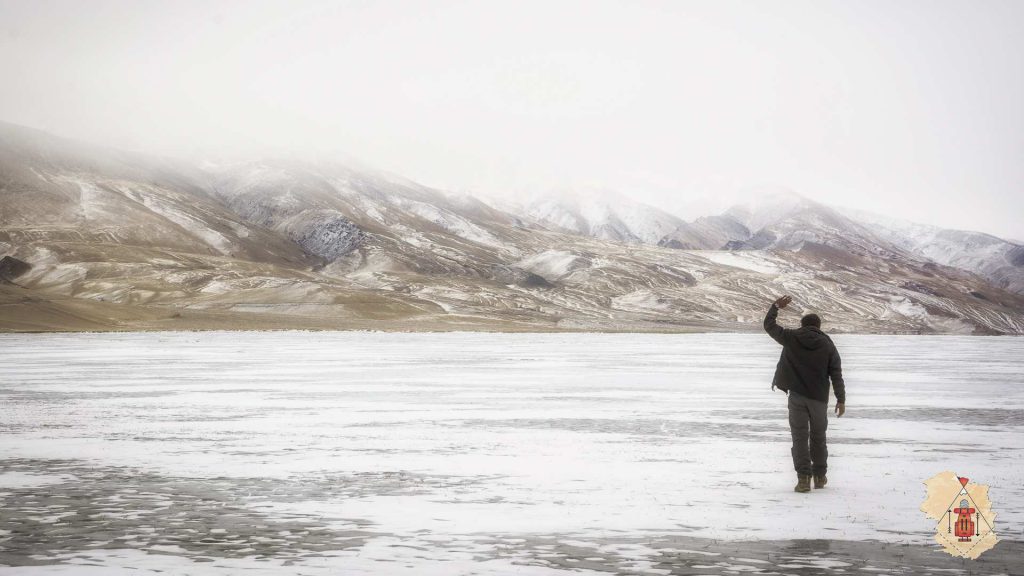 man waving hand on a frozen lake in ladakh
